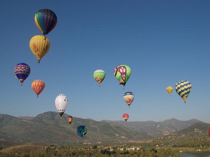 Hot air balloons in flight with mountains in the distance during summer in Park City, Utah. 