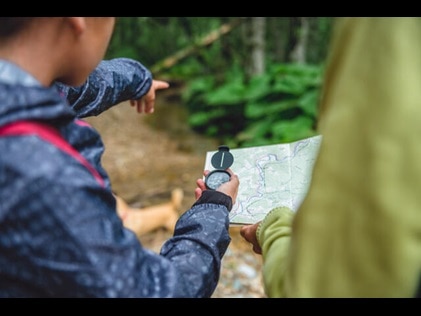 People exploring the outdoors with a map and compass. 