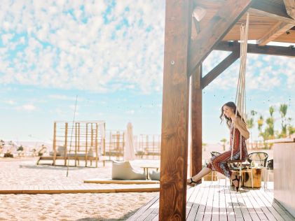 A woman sits on an outdoor swing on the beach near La Pacifica Los Cabos, a Hilton Club in Mexico