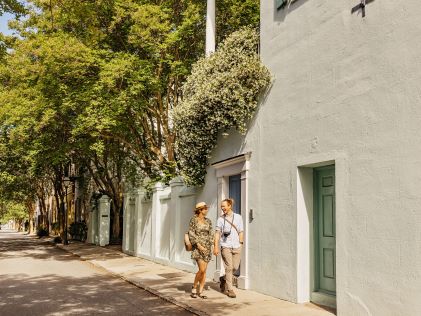 Two people walking through the historic buildings of Charleston, South Carolina