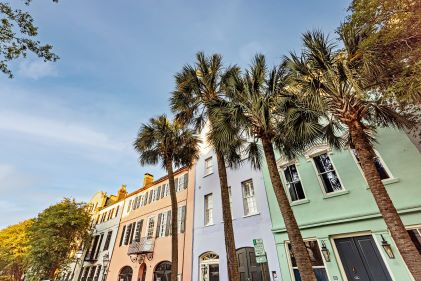 Colorful pastel row homes, palm trees, blue skies, Rainbow Row, Charleston, South Carolina.