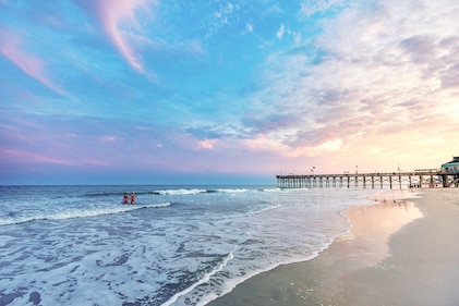 Two people enjoy a calming sunset near a pier on the beach, Myrtle Beach, South Carolina