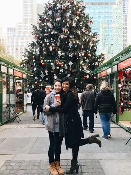 A Hilton Grand Vacations Member and her travel party posing in front of a Christmas tree at Bryant Park in New York
