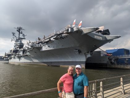 Two Hilton Grand Vacations Members in front of the battleship Intrepid in New York