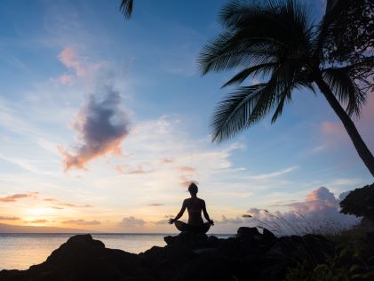 Person meditating on the beach at sunset