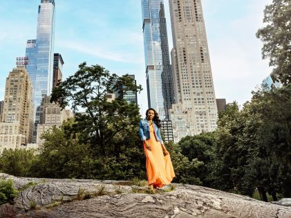 A woman in an orange dress and jean jacket in Central Park in New York City