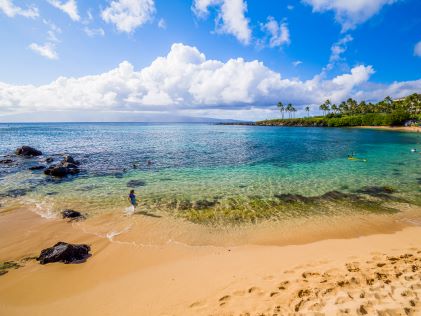 Child frolicking along stunning shoreline, golden sands, crystal clear water, sunny blue skies, Kapalua, Maui, Hawaii. 