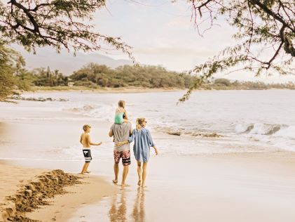 A family of four walks on a beach in Kihei, Maui, Hawaii