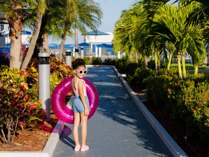 A young girl carries a pink inner tube on the way to the beach at Flaming Beach, a Hilton Vacation Club in Sint Maarten, Caribbean