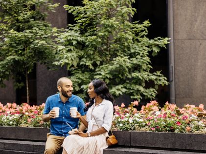 A man and woman drink coffee together outside in New York City