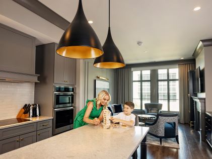 A parent and child play a game on the island counter of a spacious Suite in Liberty Place Charleston, a Hilton Club