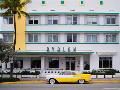 A yellow retro car outside of an art deco structure in Miami