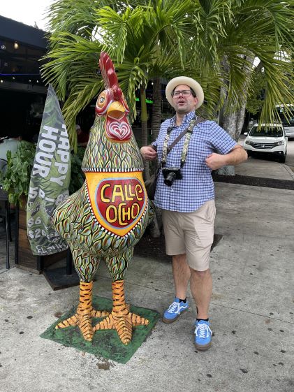 A Hilton Grand Vacations Member posing with a colorful rooster statue on Calle Ocho in Miami