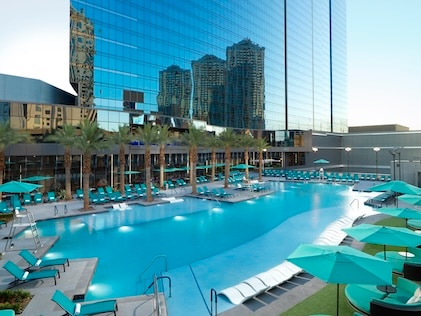 Aerial view of the sparkling blue pool and rising mirrored resort at Elara, a Hilton Grand Vacations club in Las Vegas. 