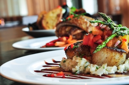 Closeup of fine dining in Las Vegas features plate with gourmet touches of colorful vegetable garnish and drizzled sauce.