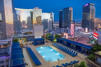 Drone image of the pool and surrounding mirrored skyscrapers at Polo Towers, a Hilton Vacation Club, seen at dusk.