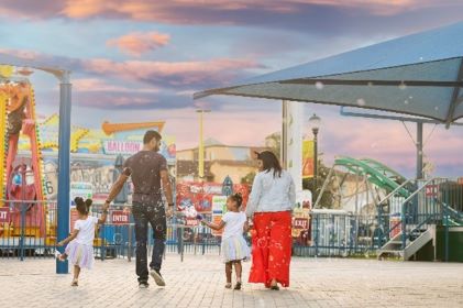 Family enjoying Orlando theme park vacation, cotton-candy colored skies overhead, Florida. 