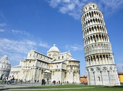 Stunning ground level image looking up at the Tower of Pisa and the cathedral complex. The white stone stands in contrast against deep blue skies.