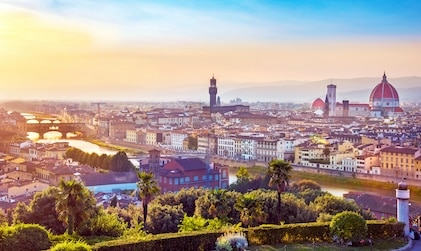 Aerial view overlooking the city of Florence, Italy as the sun sets in the distance.