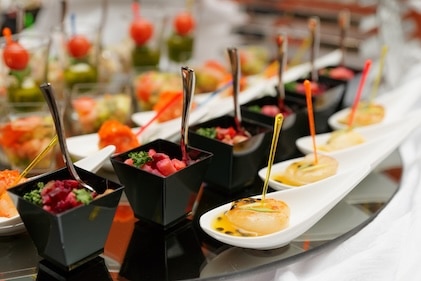 Close up of small buffet desserts and other small bites laid out in rows on a serving table.