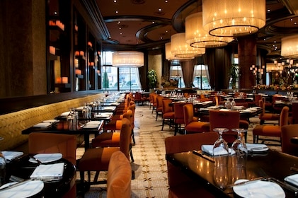 Interior photo of a stylish restaurant at Bellagio in Las Vegas. Crystal chandeliers hang above tables with deep wood tones and red velvet chairs.